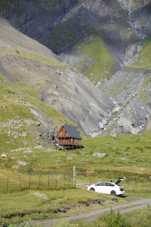 a car parked on a grassy road in front of mountains