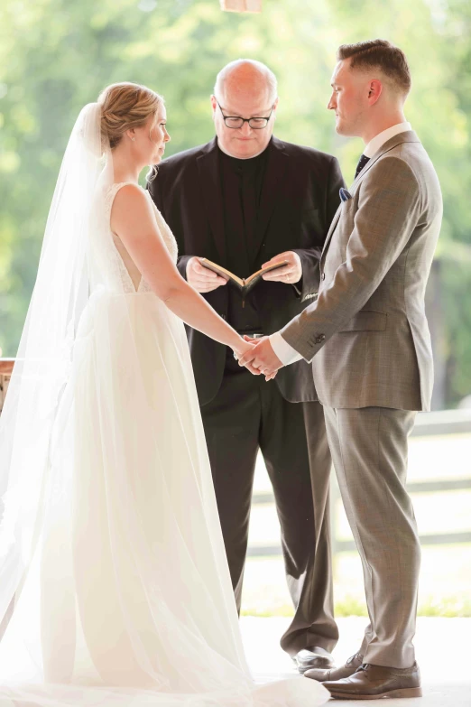 a bride and groom holding hands during their wedding ceremony