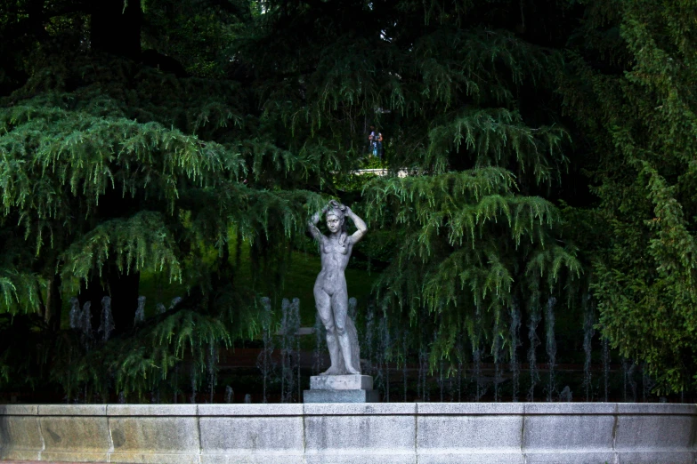 a statue sits in the foreground under trees