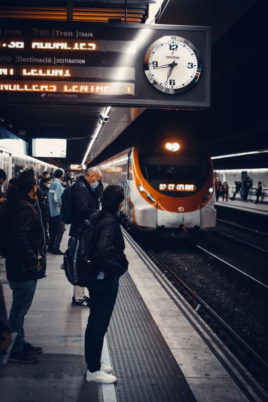 a clock in a train station above a crowd of people