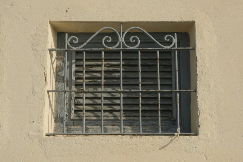 a small window with bars, a grill and curtain over it