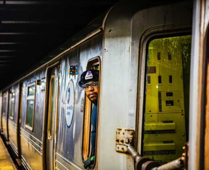 a man with his face partially hidden by a door near the subway