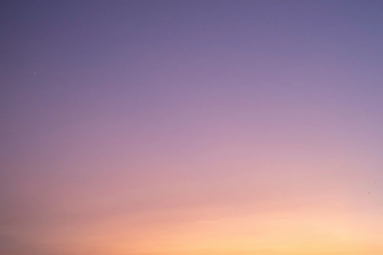 two surfers standing next to each other while a sunset is behind them