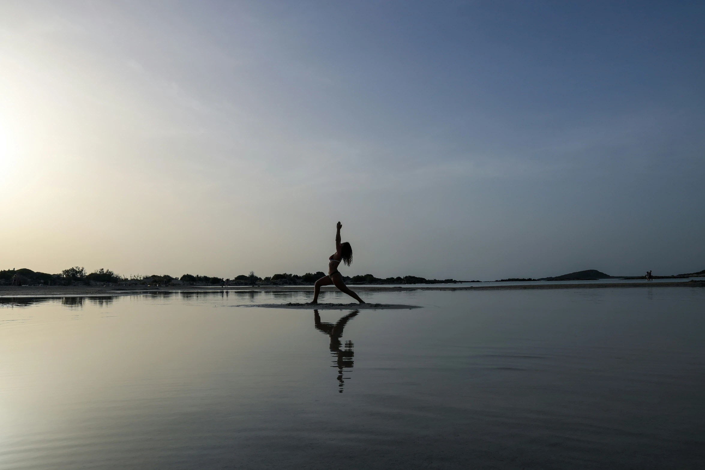 someone doing yoga on the beach at sunset