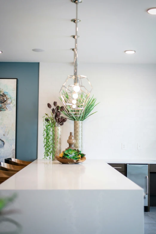 a chandelier hanging over a kitchen island in front of a painting