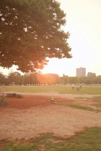 people playing baseball on a field in the sun set