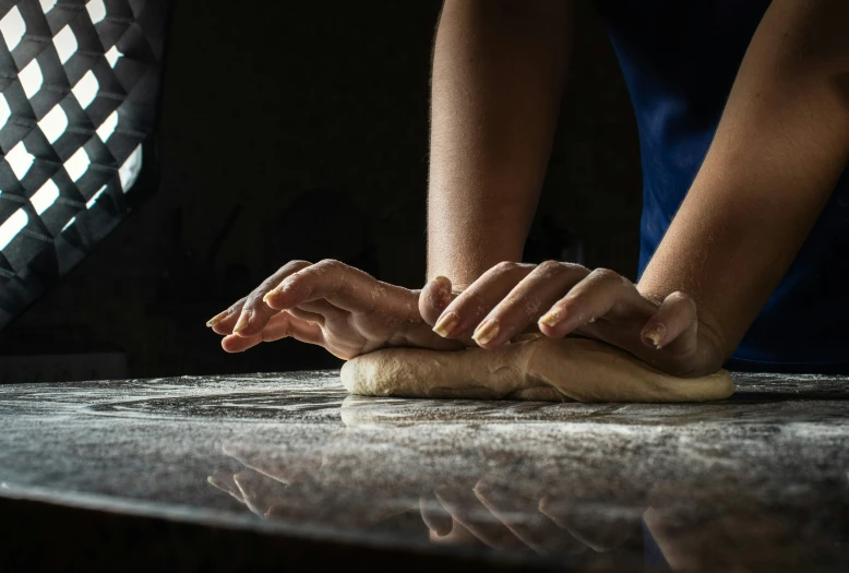 someone kneading dough onto some flour