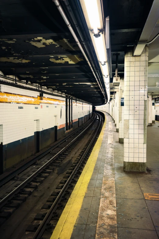 an empty train platform next to some tall brick pillars