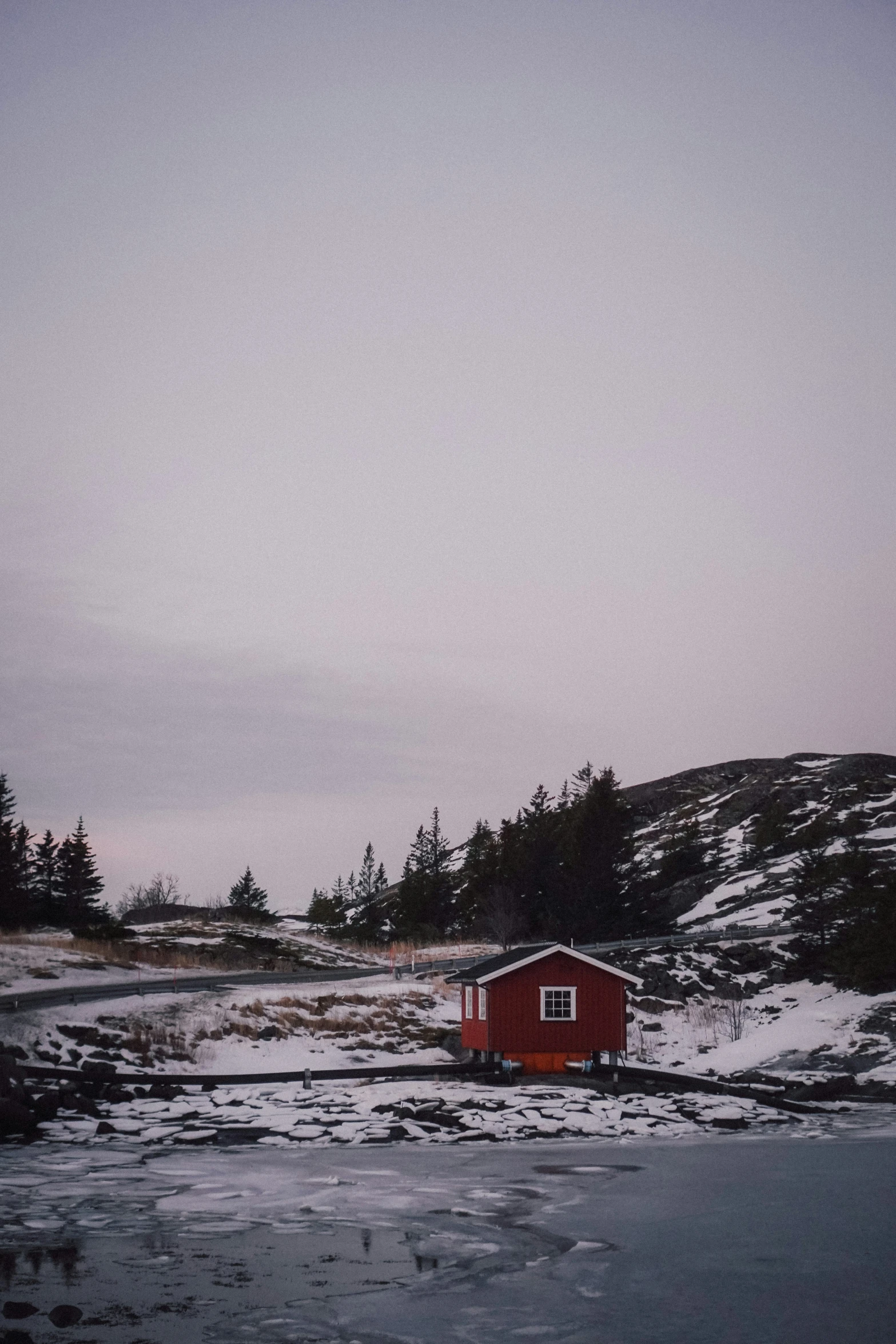 a red house in the middle of an icy field