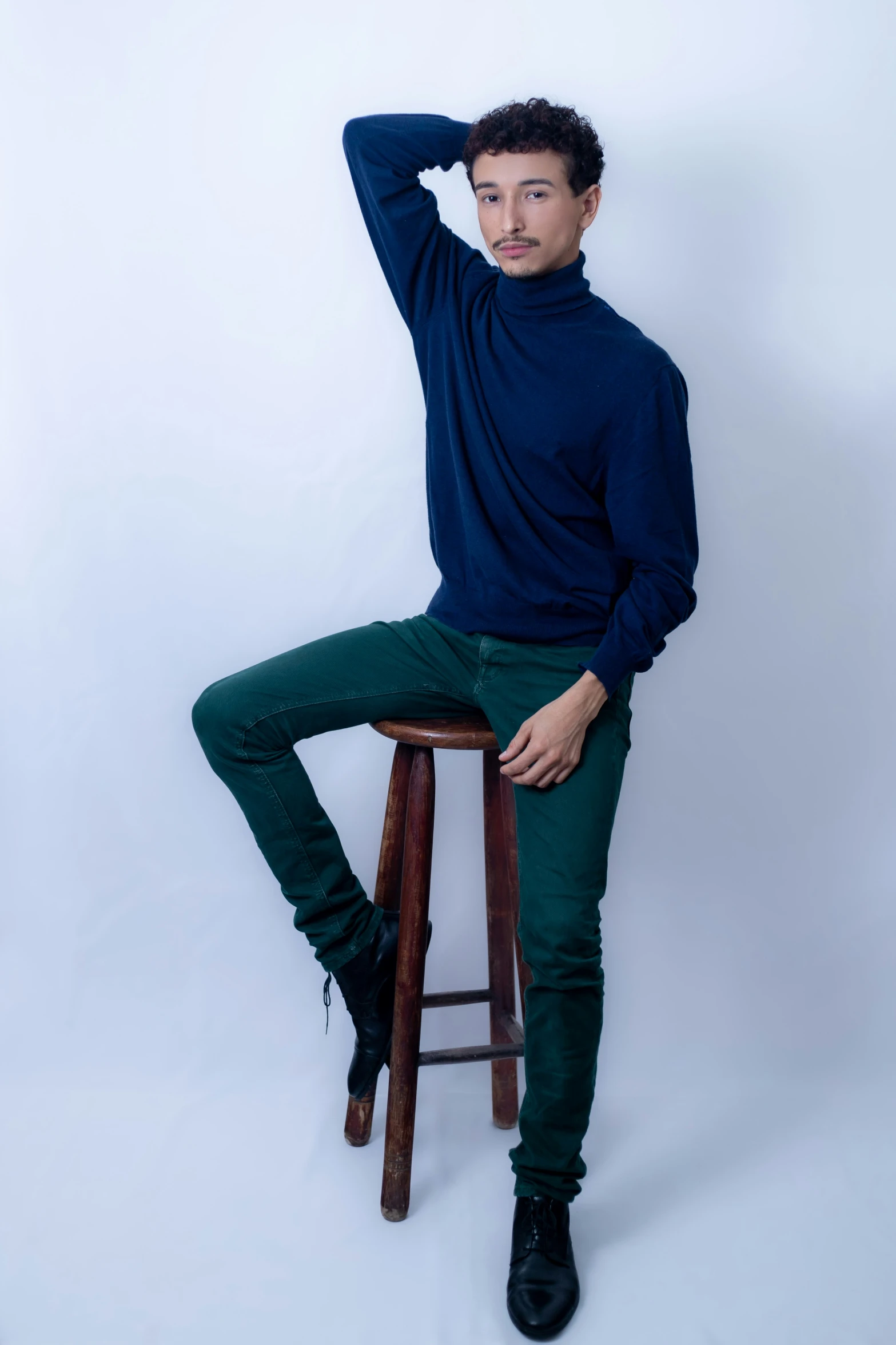 a man in dark blue sweater sitting on a stool