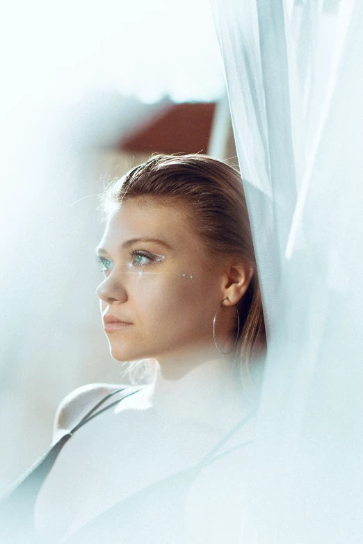 woman sitting in a chair wearing a white top looking out the window