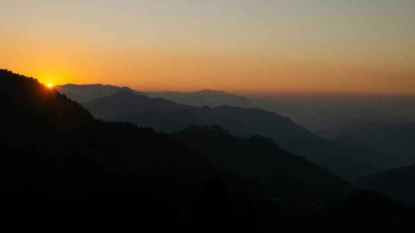 the sun setting over a mountains ridge with clouds