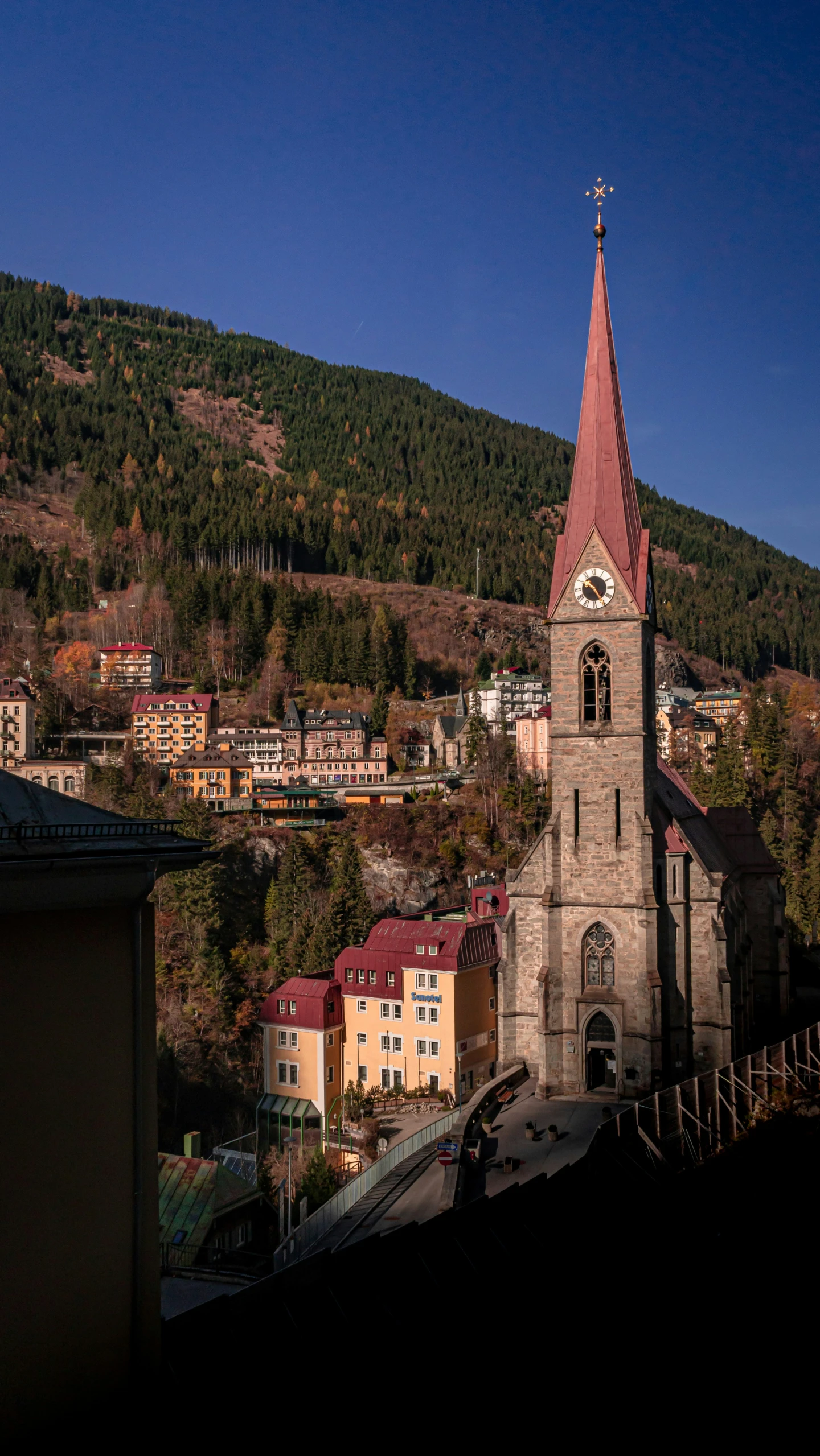 a church with a steeple and mountains in the background