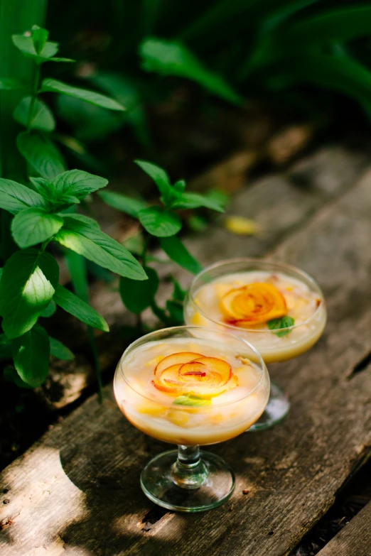 two champagne filled beverages sitting on a wooden bench