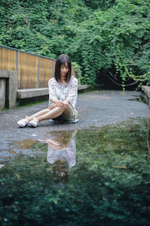 a woman is sitting on the ground while she is squatted on some concrete