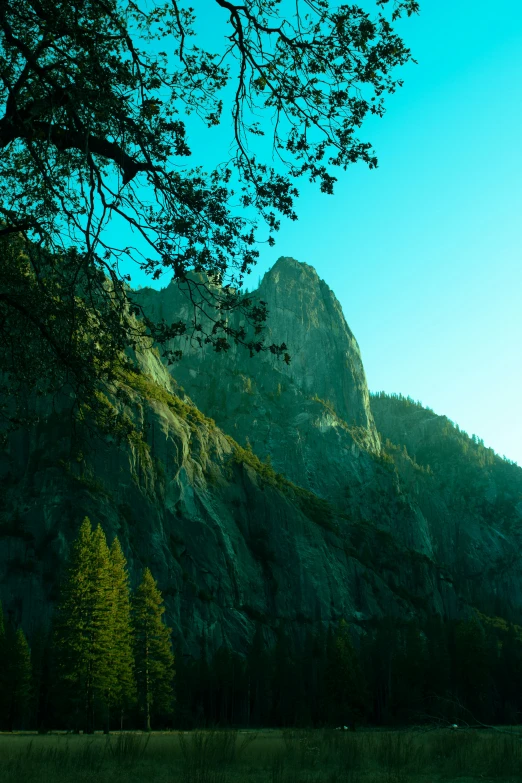 a mountain with trees in the foreground, and the sky above it