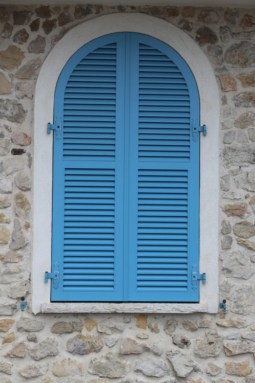 an arched window with blue wood shutters