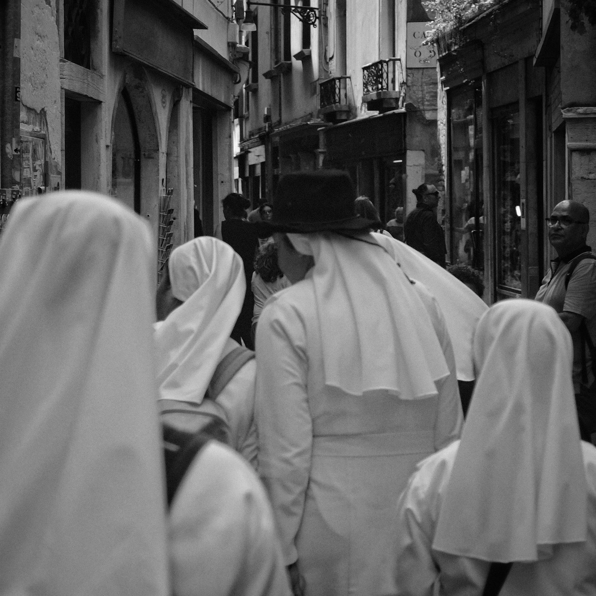 a group of people in white dresses walking down the street