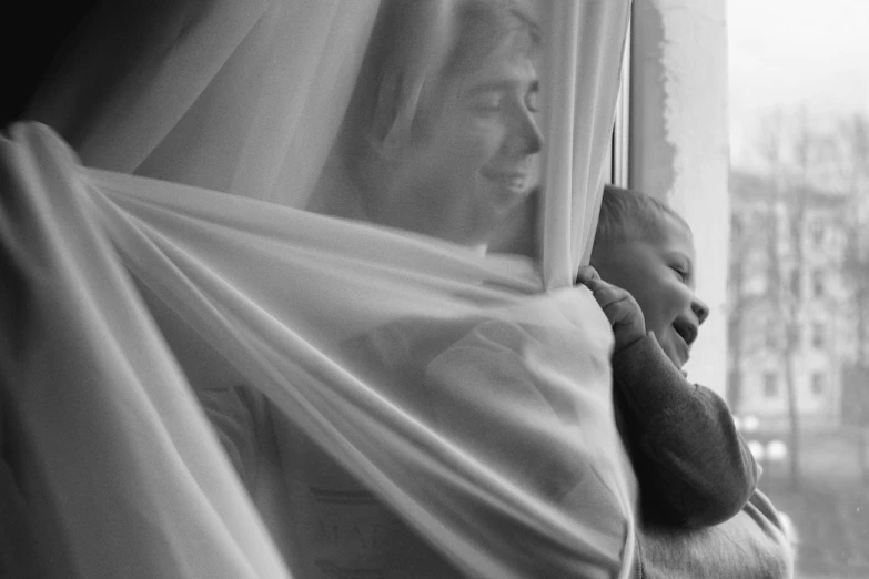 a baby wrapped in a blanket looking out a window