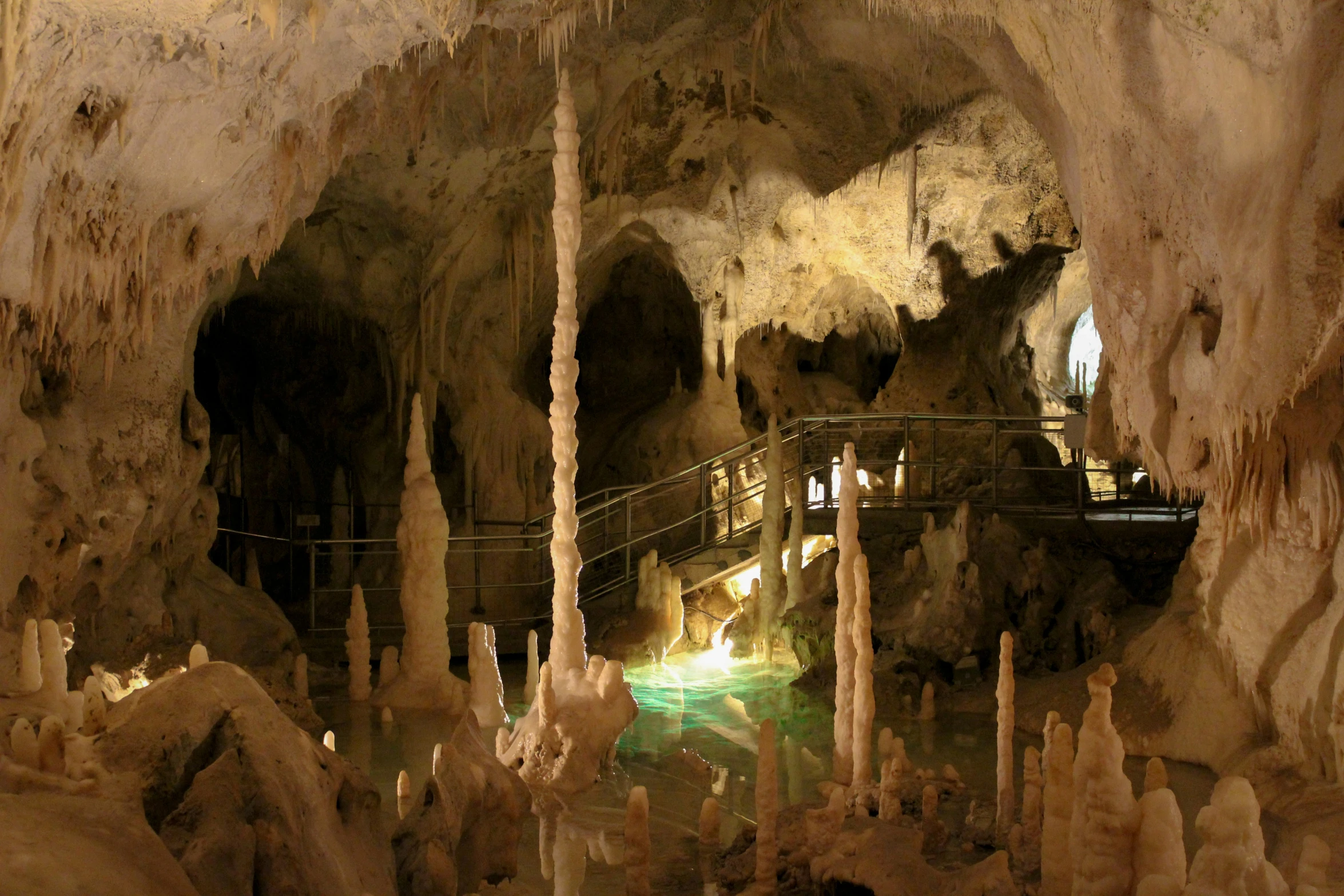 people are walking in an indoor cave near the waterfall