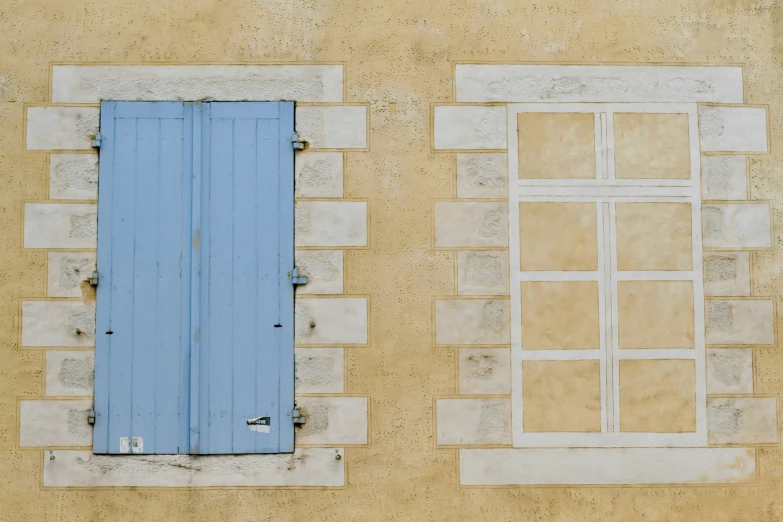 an outdoor area with an open blue door and a wall that has windows on it