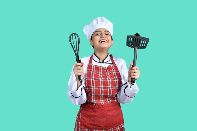 a woman holding two spatulas and a whisk