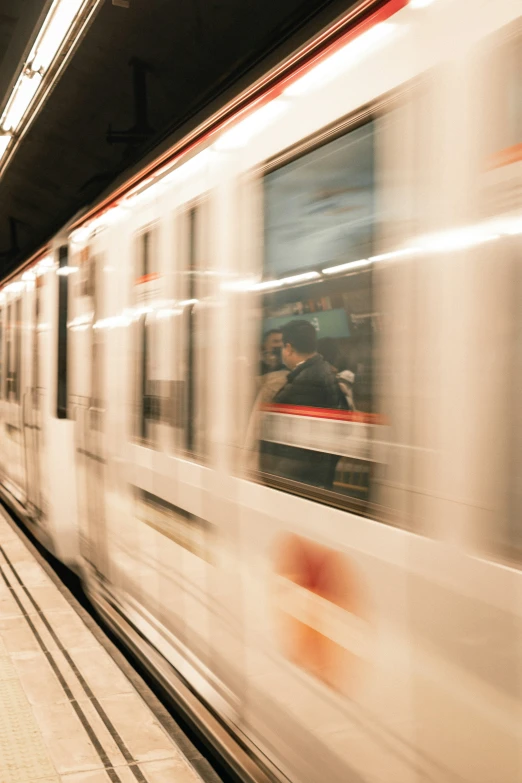 a commuter train moving past a platform at night