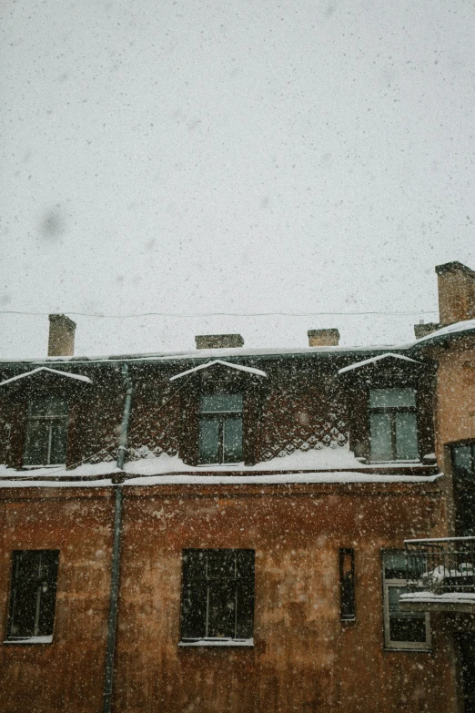 a brick building with snow falling on top and windows