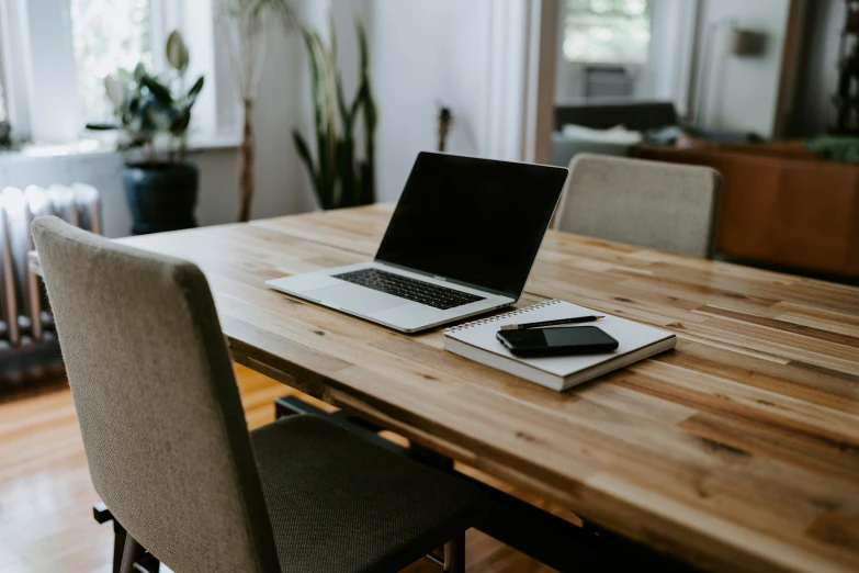 a laptop sits on a wooden table with books and an external mouse