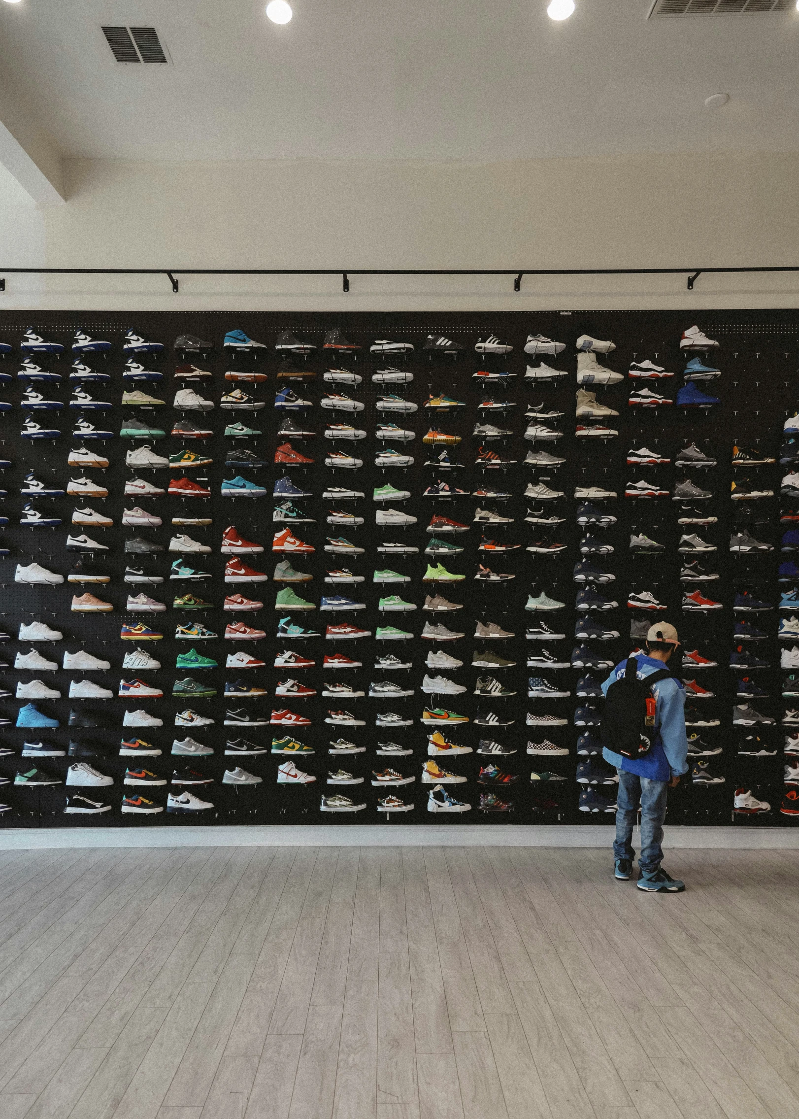 person standing in front of wall full of pairs of shoes