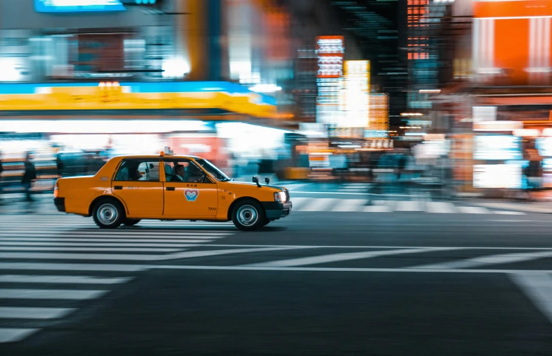 a yellow taxi driving down the street at night