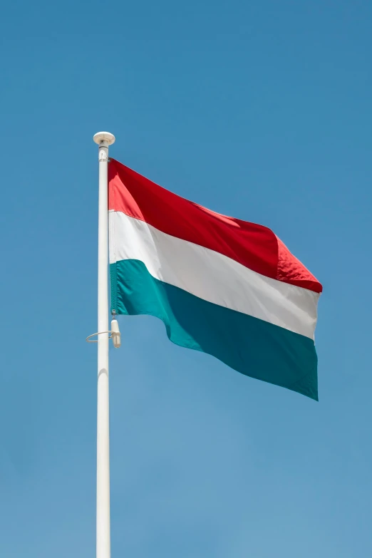 a big red, white and blue flag flying on top of a flag pole