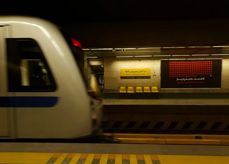 a white train traveling down tracks next to a station