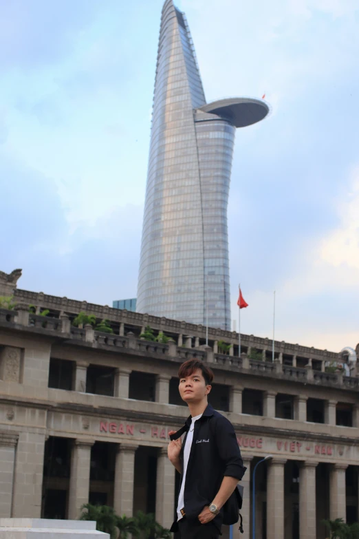 a young man is standing by a tall skyscr