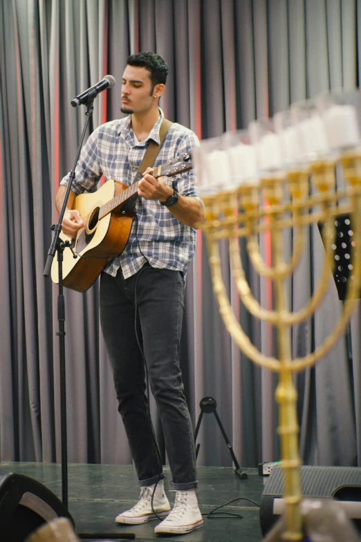 a man with guitar standing in front of microphone on stage