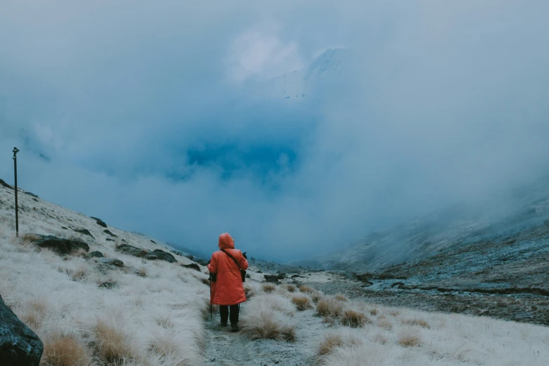 the woman is walking on the hill towards the mountain