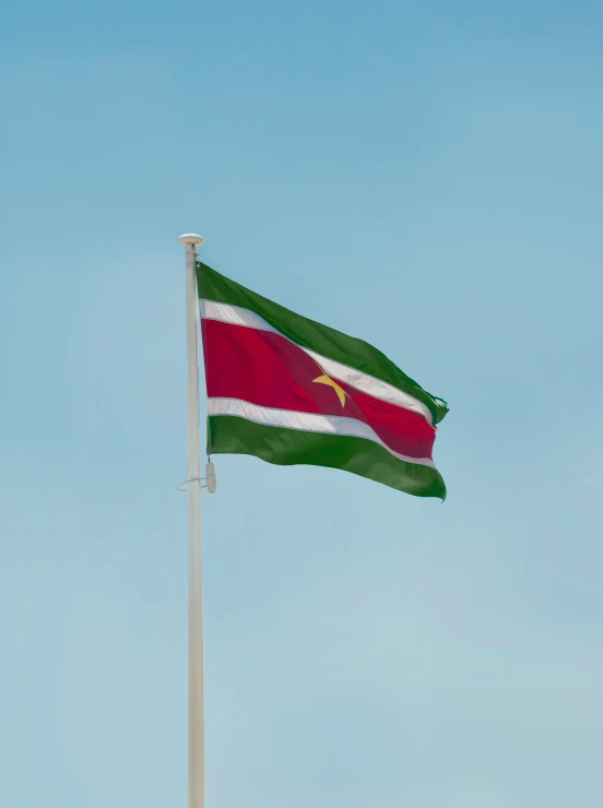 a flag flying in the wind on top of a white pole