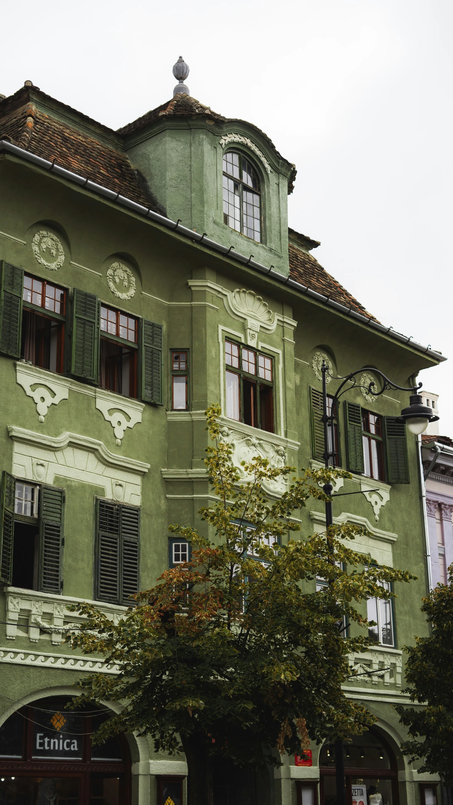 a tall building with lots of windows and green roofing