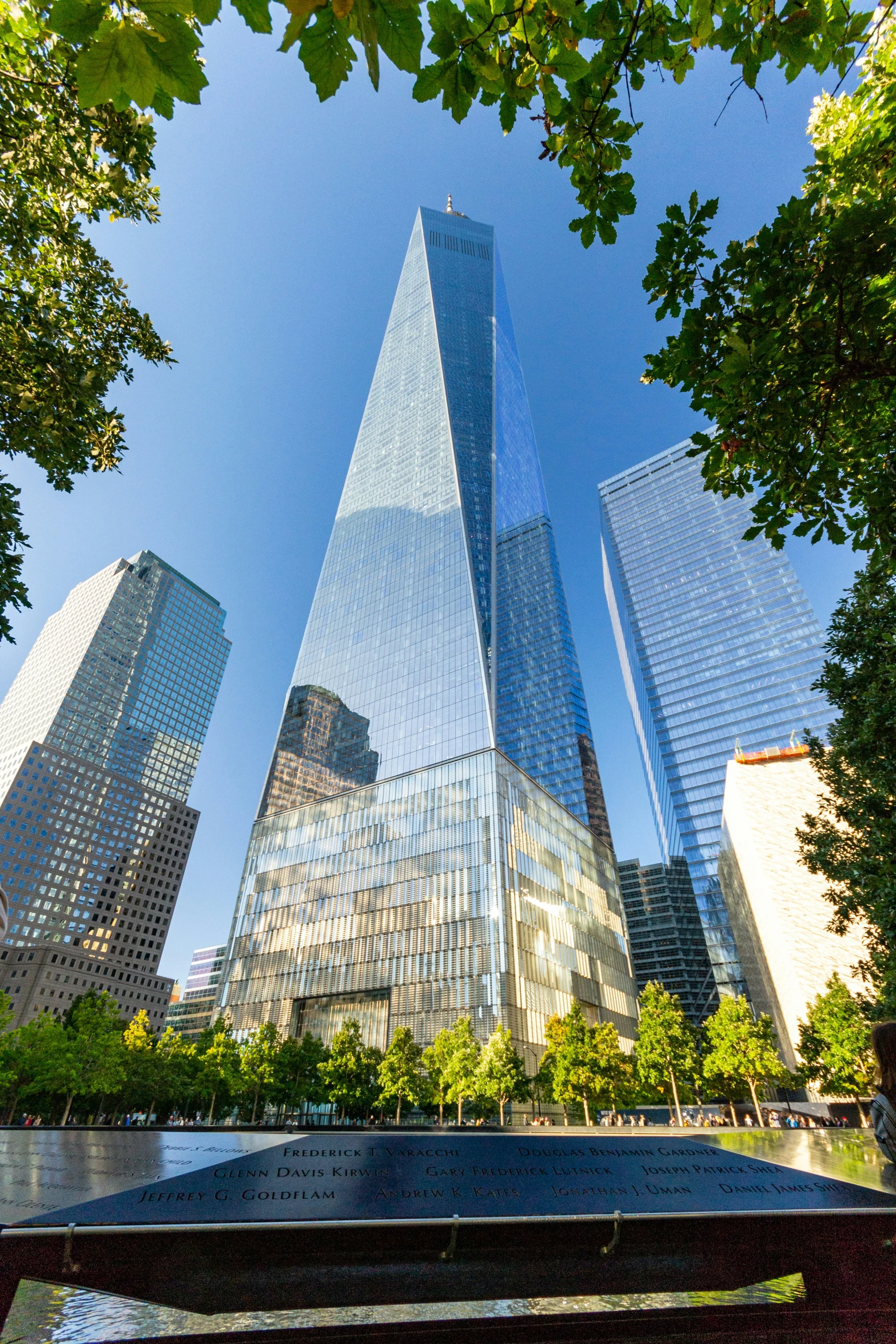 a bench in the middle of a park with two tall buildings behind it