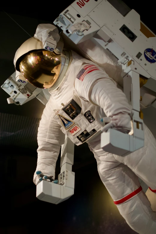an astronaut in white suit, with his foot and head strapped to the side of the space station