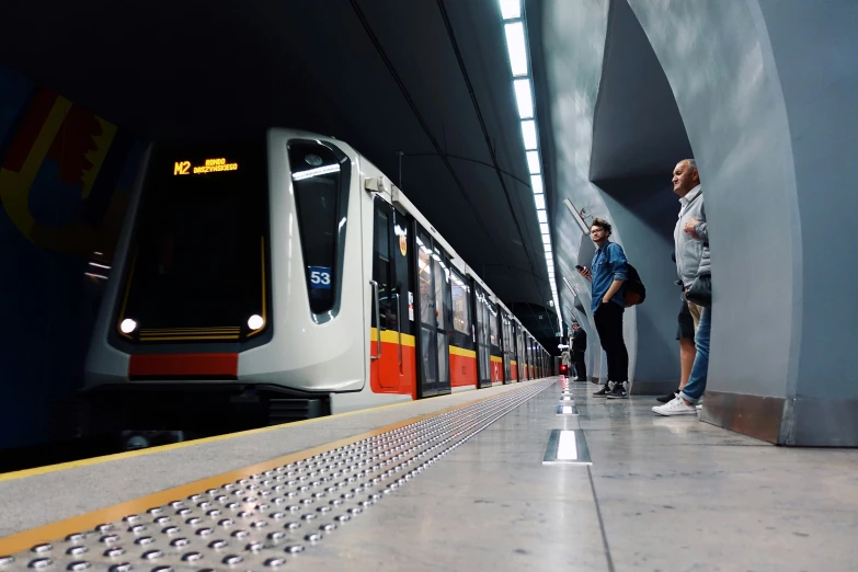 people are standing on the platform next to a subway train