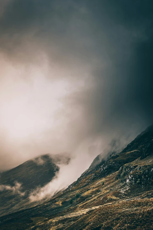 a mountain under a cloudy sky with the wind blowing