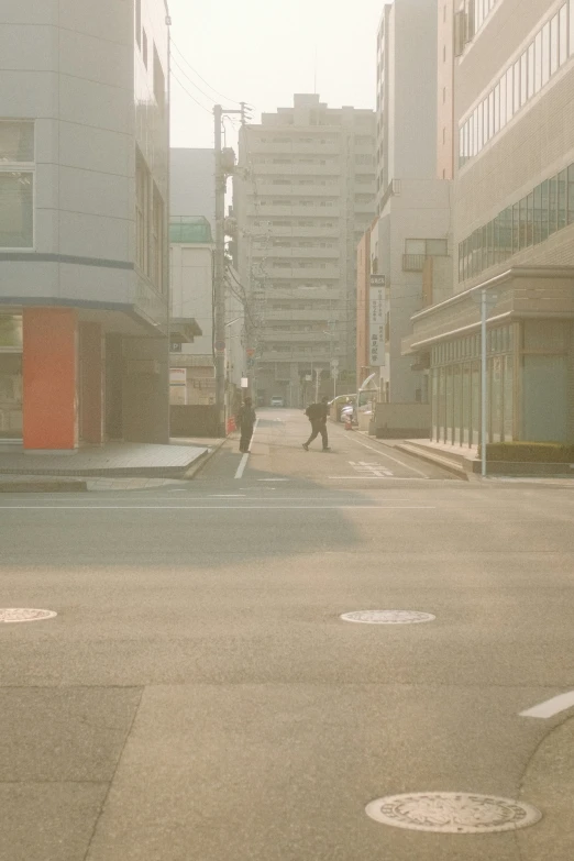 a person crosses the street between shops and a city