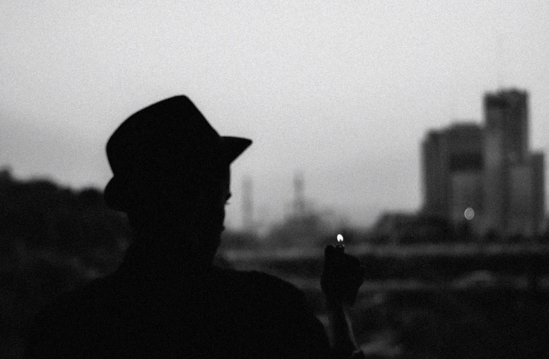 a silhouette of a man with a cigarette in his hand