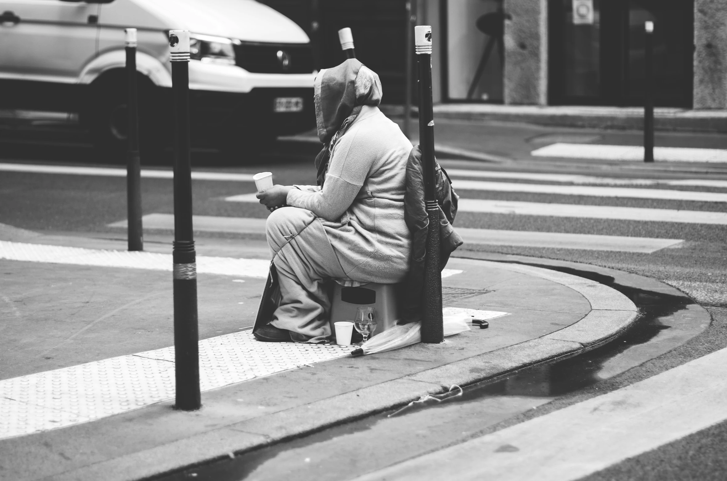 a woman in a suit sits on a street corner with a backpack on her lap