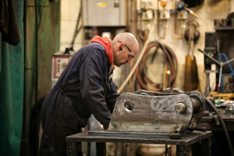 a man standing next to a machine working on the front of it