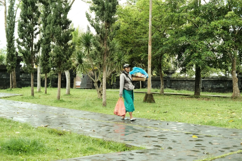 a person walking down a wet walkway carrying a blue bag