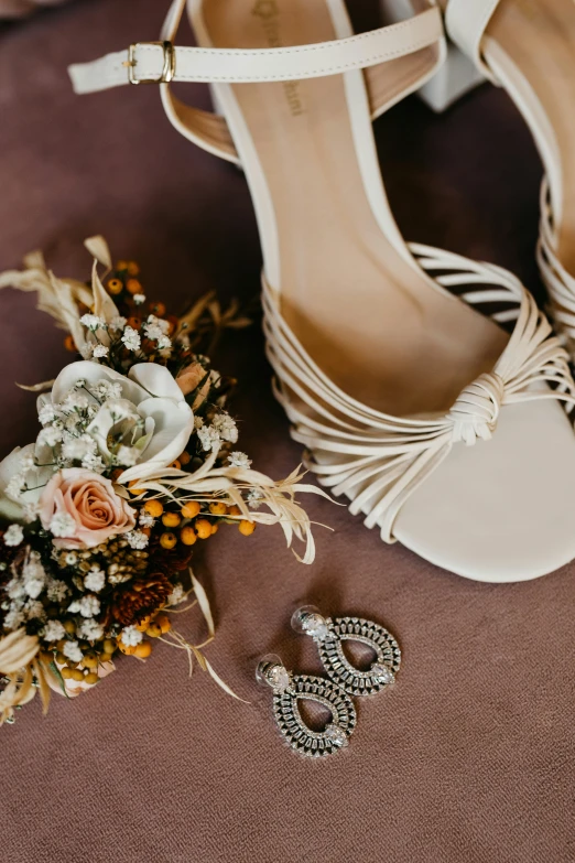 a wedding dress and flowers on the ground with heels