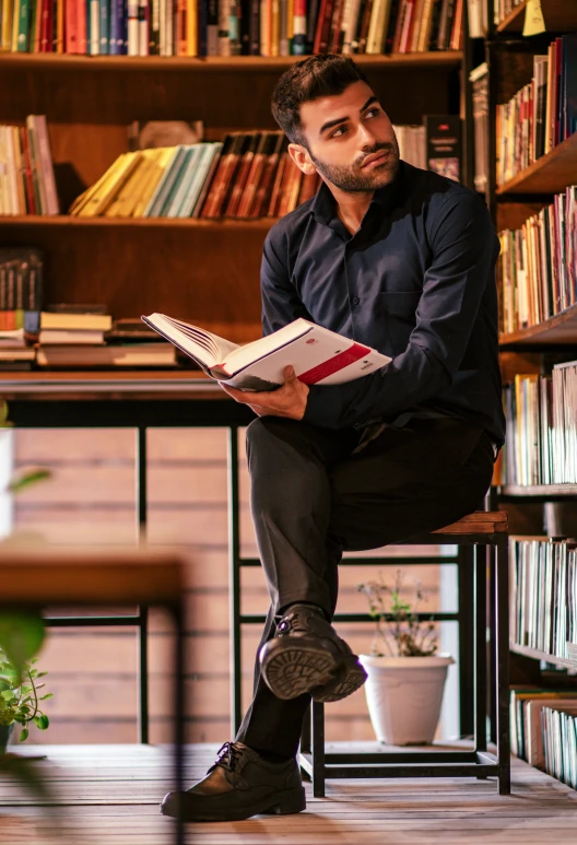 the man is reading in front of the bookcase