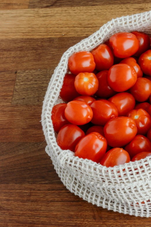 a jumble of ripe tomatoes in a white linen sack